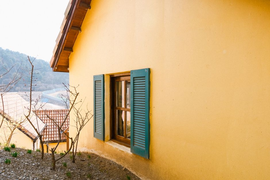 A yellow painted house with blue shutters