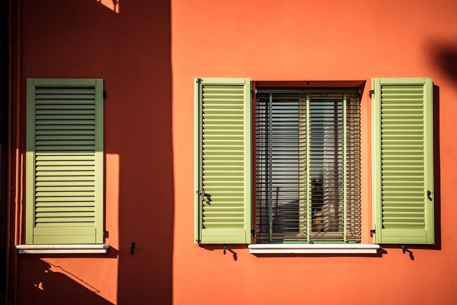 An orange painted wall with green shutters