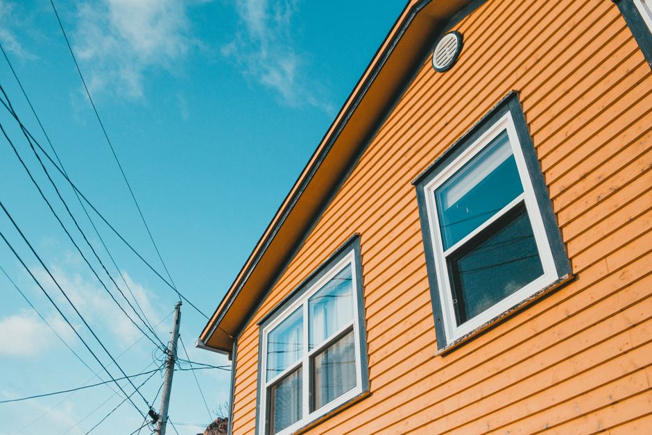 A yellow painted wooden house against a blue sky