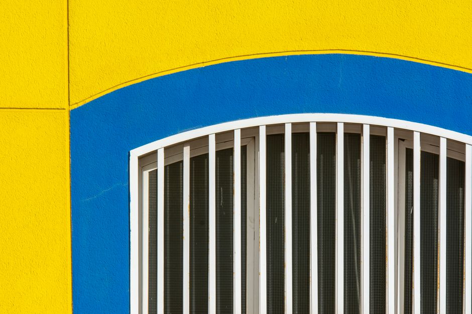 A yellow and blue painted wall around an arched window