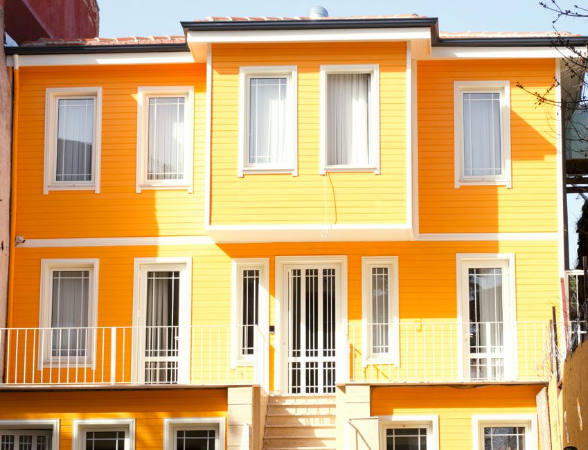 A yellow painted house with white framed windows and door